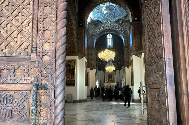 ورودی کلیسای جامع اچمیادزین، اولین کلیسای جامع جهان، با درهای چوبی منبتکاری شده و چلچراغهای باشکوه