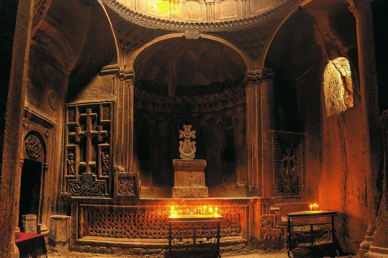 فضای داخلی صومعۀ سنگی گغارد که با نور شمعهای روشن و محیطی معنوی