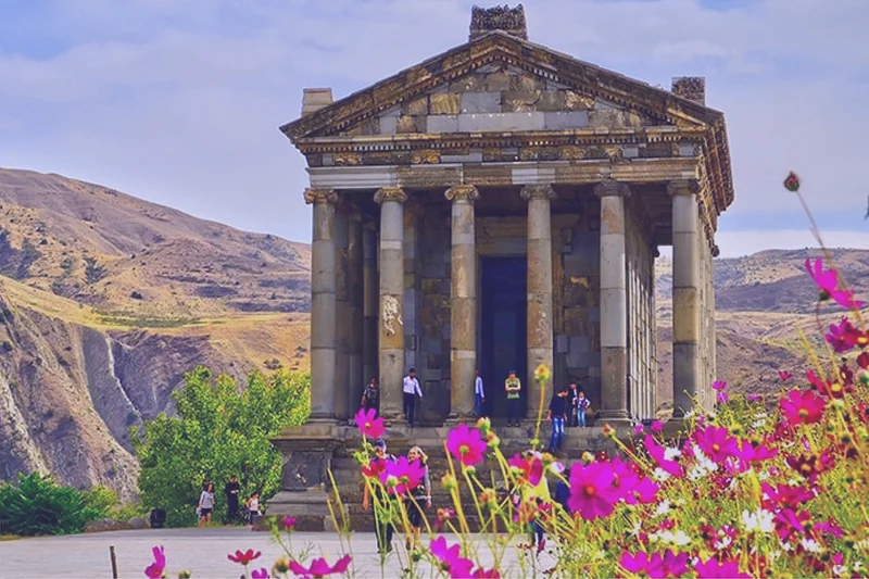 تصویری از معبد گارنی در یک روز آفتابی و میان گلهای وحشی