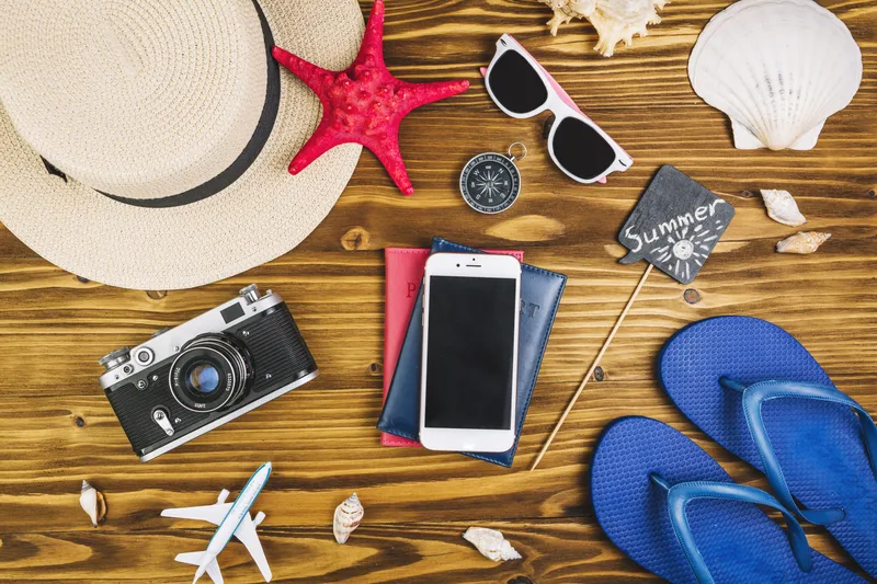 تصویری از برخی وسایل موردنیاز برای سفر تابستانی. مانند صندل، عینک آفتابی و کلاه لبهدار