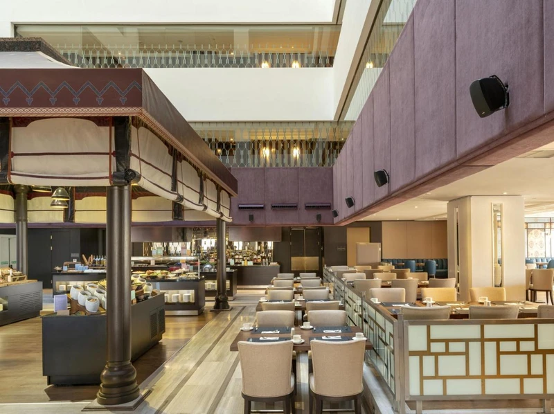 سالن رستوران مدرن هتل بارسلو استانبول، با میزهای چیده&zwnj;شده برای غذاخوری و بوفه سلف&zwnj;سرویس در سمت چپ.