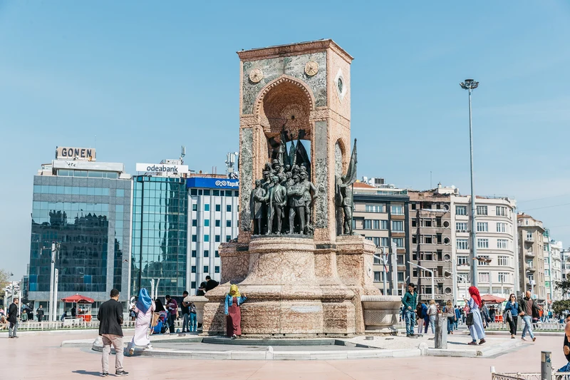 نمایی از مجسمه جمهوریت (Cumhuriyet Anıtı) در مرکز میدان تکسیم استانبول، با حضور گردشگران و ساختمان&zwnj;های مدرن اطراف در پس&zwnj;زمینه.