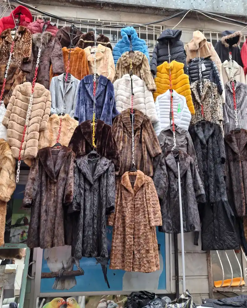 مجموعهای از پالتوهای زمستانی در رنگهای مختلف، که در غرفهای در جمعه بازار لباس فیندیکزاده استانبول آویزان شدهاند